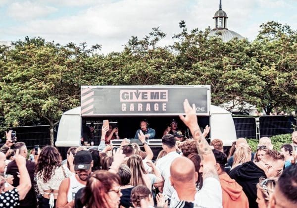 Give me garage vw dj booth at hidden festival with crowd of people dancing