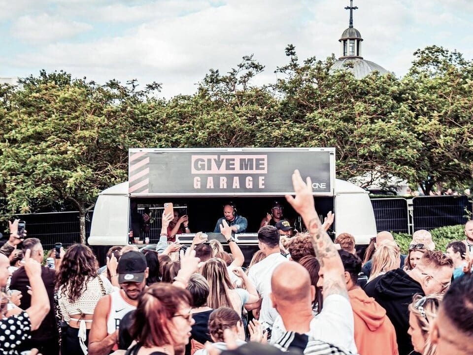 Give me garage vw dj booth at hidden festival with crowd of people dancing
